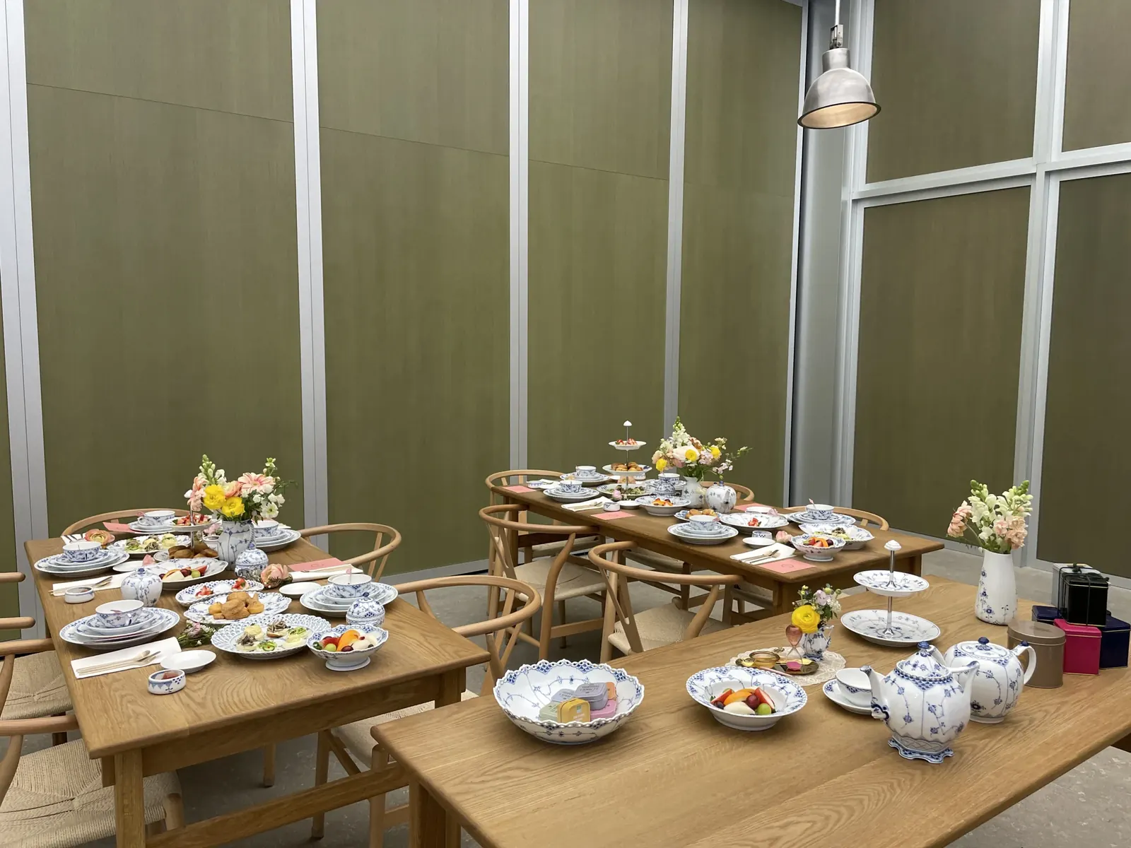 올리브색 벽면의 넓은 룸에 3개 테이블이 애프터눈티로 세팅된 전경