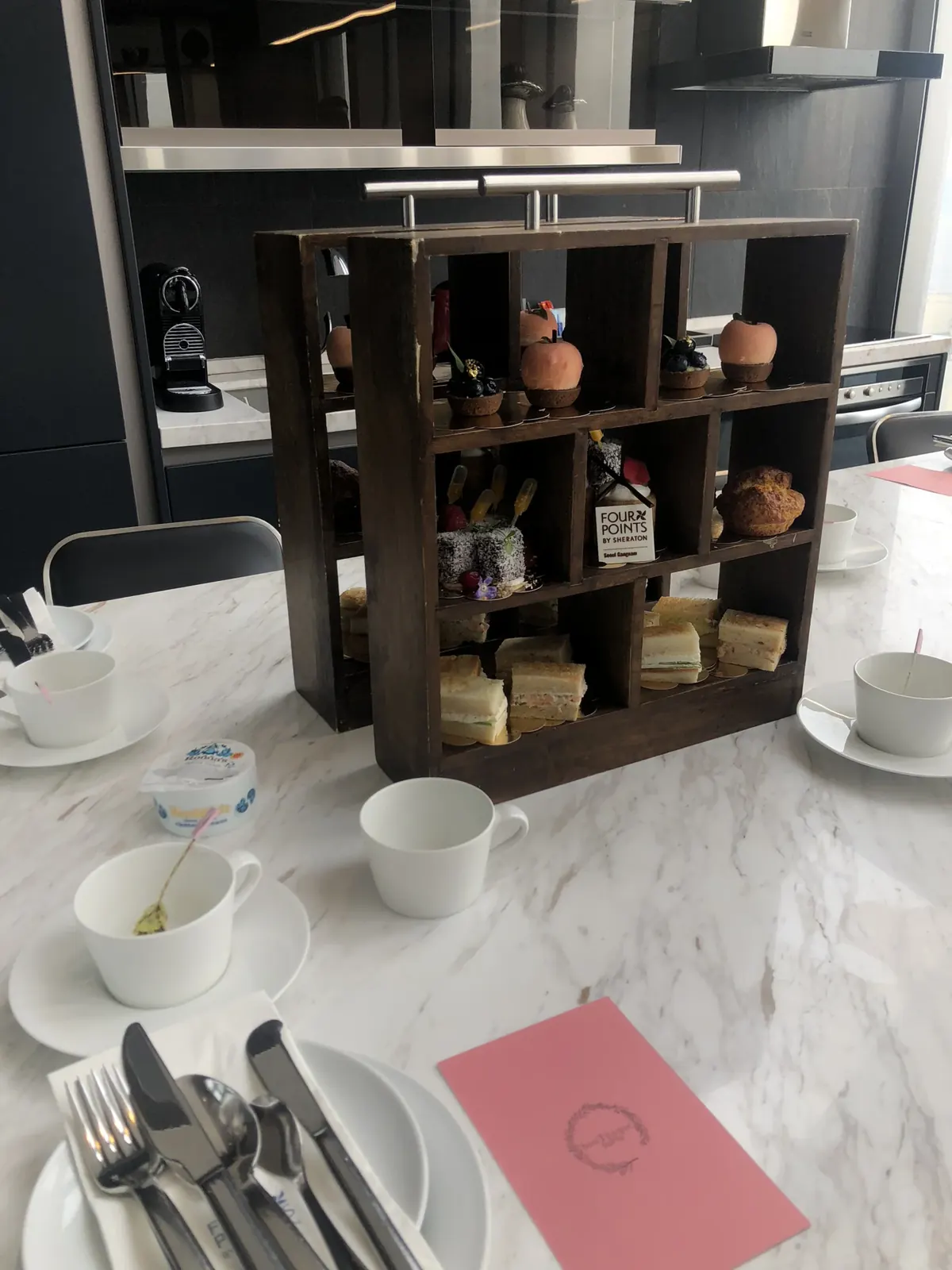 목재 큐브 선반형 애프터눈티 스탠드 클로즈업, 'FOUR POINTS BY SHERATON' 카드가 놓인 모습