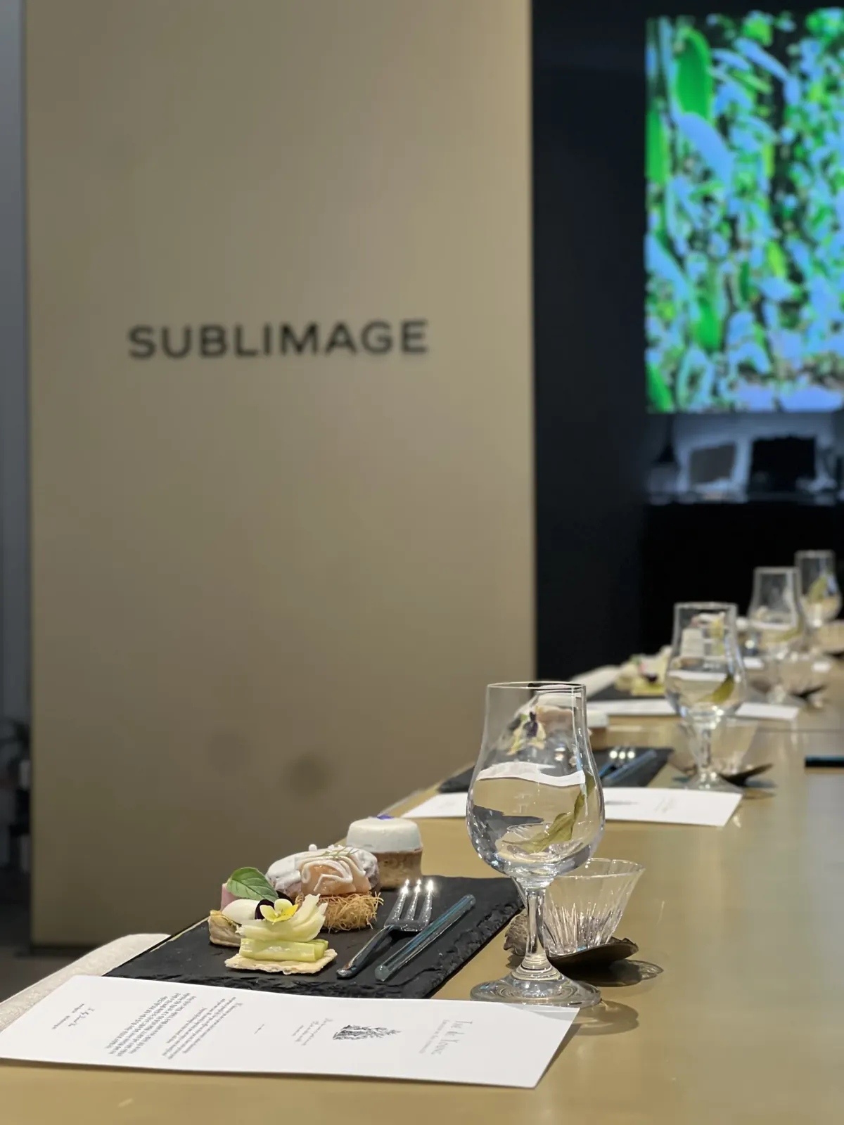 CHANEL SUBLIMAGE 사이니지 벽면 앞, THE de YOUNG 카드와 슬레이트 트레이 위 프티푸르 세팅 클로즈업