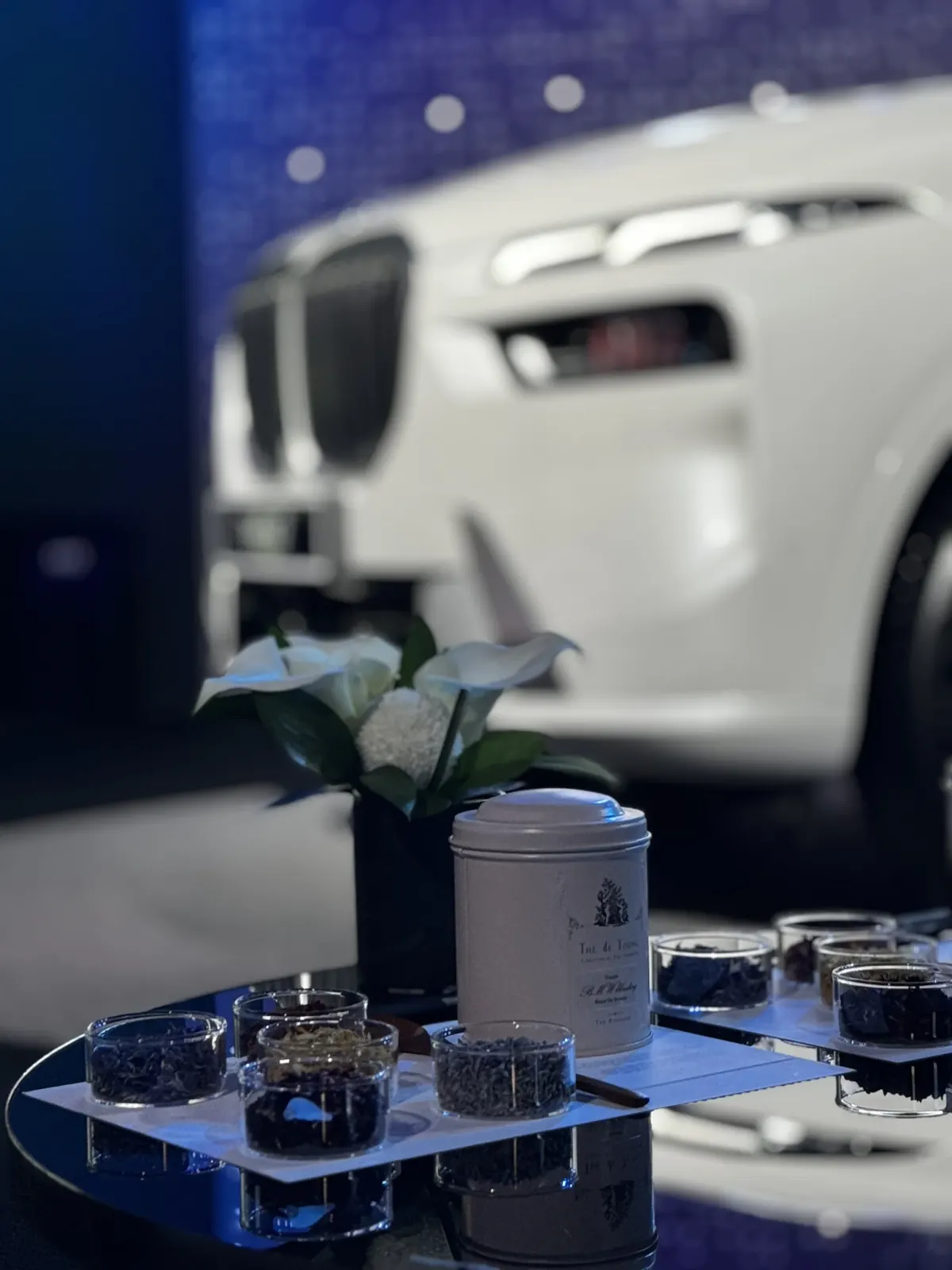 BMW 브랜드 행사장 어두운 톤 와이드샷, 스태프가 이동하며 마무리 점검하는 모습